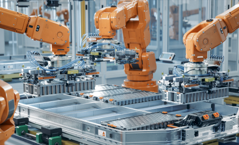 Automated robotic arms in an orange hue assembling electric vehicle battery packs on a modern manufacturing assembly line, showcasing advanced production technology and efficiency.