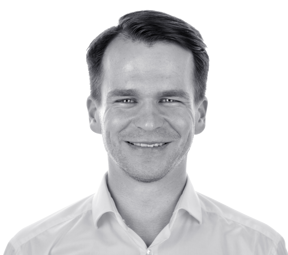 Headshot of Łukasz Wicher, CEO of andea, smiling and wearing a white dress shirt. He is a key figure in providing MES and APS solutions for manufacturing.